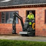 hyundai-hx10a-z-compact-excavator-Compact excavator with operator in neon hi-vis working beside a brick building with windows and open doorway